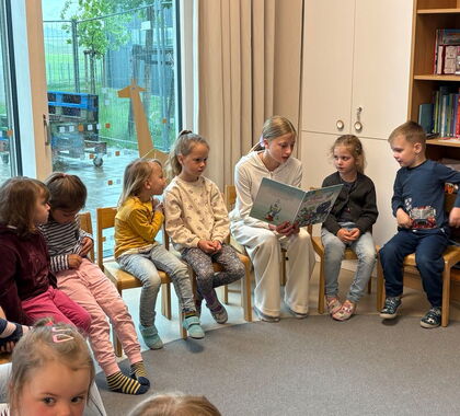 Ein junges Mädchen liest Kindern ein Buch vor