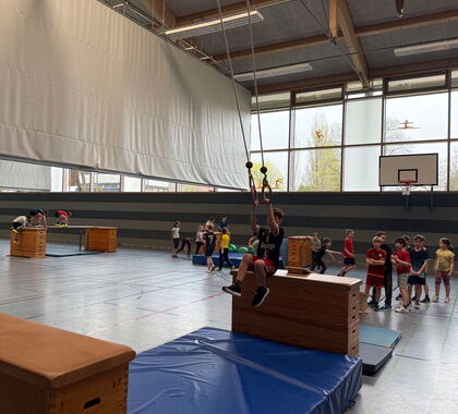 Ein Schüler schwingt sich von einem Sportkasten mit einem Schwingseil