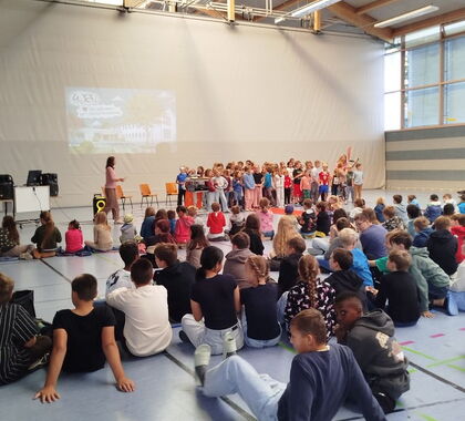 Schüler sitzen in einer Sporthalle auf dem Boden