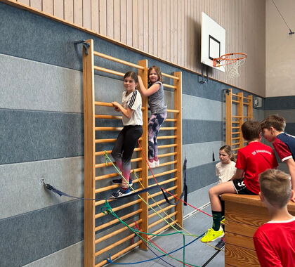 Zwei Schülerinnen klettern an einer Sprossenwand