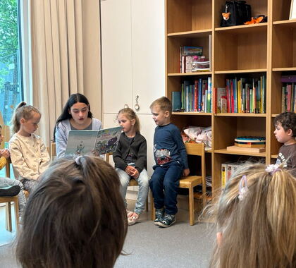 Eine junge Frau liest Kindern ein Buch vor