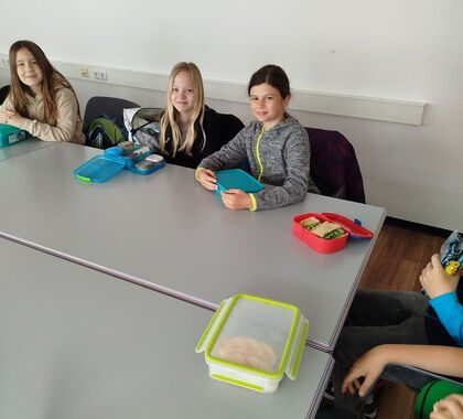 Schüler sitzen gemeinsam an einem Tisch mit Brotzeit