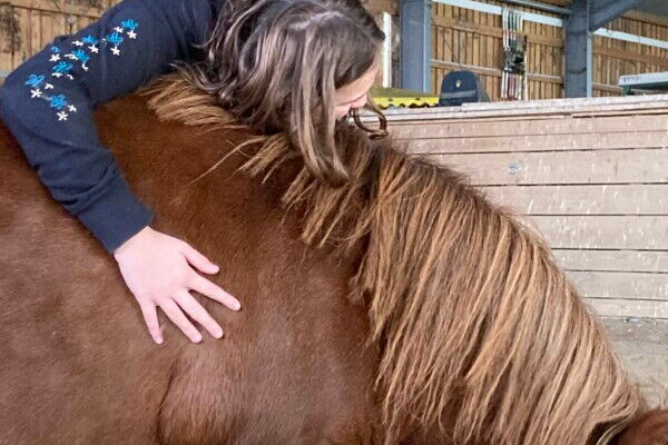 Ein Mädchen lehnt über der Schulter eines Ponys
