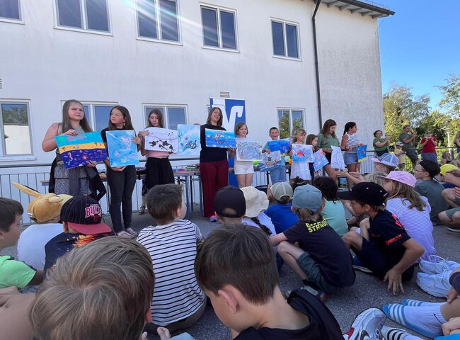 Eine Gruppe von Schülern steht auf der Bühne und präsentiert Bilder