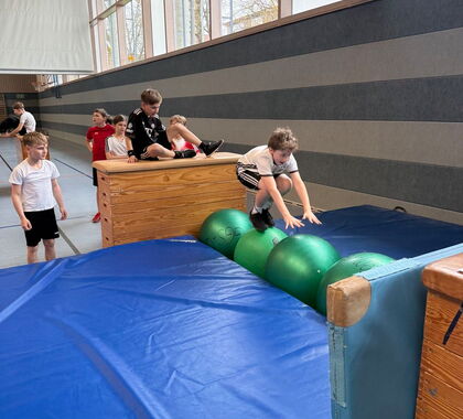 Ein Schüler springt beim Sportunterricht auf eine Matte