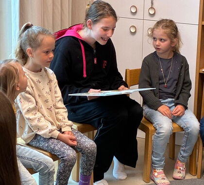 Ein junges Mädchen liest Kindern ein Buch vor