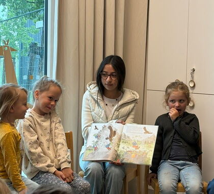 Ein junges Mädchen liest Kindern ein Buch vor