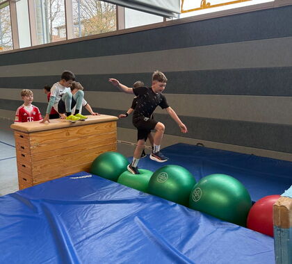 Ein Schüler sprintet über große Gymnastikbälle