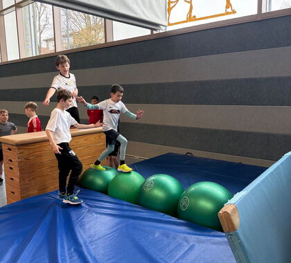 Ein Schüler sprintet über große Gymnastikbälle